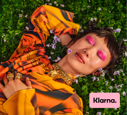 A hip young woman lounging in a field with the Klarna logo applied in the corner
